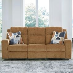 a couch with two pillows on it in front of a window and carpeted floor