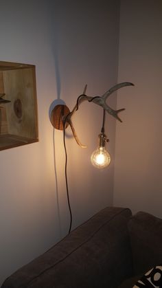 a deer antler head mounted to the wall next to a light bulb on a wall