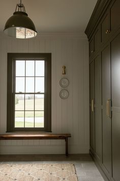 an empty room with a window, bench and cupboards in front of the window