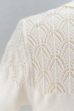 the back of a white sweater with an intricate design on it's chest and shoulders