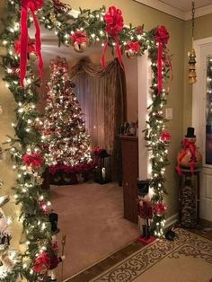 a christmas tree decorated with red bows and lights in a living room next to a doorway