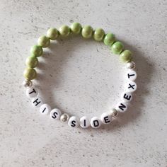 "A pretty beaded breastfeeding reminder bracelet. The bracelet consists of pale green acrylic beads. The coloured beads are known as miracle beads which are a type of resin bead with a lacquered surface which makes them incredibly shiny. They almost look like a bead within a bead. The beads measure approximately 8 mm. The bracelet measures 7 inches but as it is made from elastic it will stretch to accommodate most wrist sizes. There are silver plated spacer beads between the lettering. The wording on the bracelet reads \"This Side Next\". If you forget which side your baby has last fed from this bracelet can help. As it is a stretch bracelet made from elastic it is easy to swap form one wrist to the other, simply roll down over your wrist to avoid overstretching the bracelet. You bracelet Green Personalized Bracelets With Round Beads, Personalized Green Bracelets With Round Beads, Green Name Bracelet With Letter Beads, Green Beaded Name Bracelet For Friendship, Green Letter Beads Bracelets For Friendship, Personalized Green Beaded Bracelets For Friendship, Green Beaded Bracelets With Letter Beads For Friendship, Green Friendship Bracelets With 8mm Beads As Gift, Green Beaded Friendship Bracelets With Letter Beads