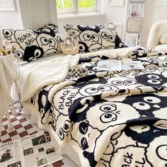 a bed with black and white designs on the comforter, pillows and blankets in front of a window