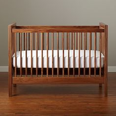 a wooden crib with white sheets and pillows on the bottom bed, against a black background