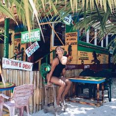 a woman in a black bathing suit sitting at a table with some signs on it