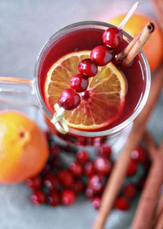 a close up of a drink in a glass with oranges and cinnamon sticks