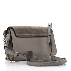 This is an authentic CHLOE Suede Calfskin Mini Faye Shoulder Bag in Motty Grey. This stylish shoulder bag is crafted of smooth calfskin and suede leather in light grey. The bag features an adjustable leather shoulder strap and polished silver and gold hardware including a decorative ring attached to a clasp and chain. The flap opens with a magnetic snap to a suede interior with leather card slots. Stylish Shoulder Bag, Silver And Gold, Suede Leather, Gold Hardware, Card Slots, Calf Skin, Slots, Chloe, Light Grey