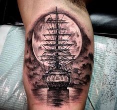 a man's leg with a ship in the water under a full moon tattoo