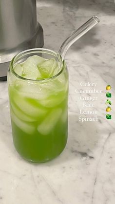 a glass filled with green liquid next to a blender on a marble counter top