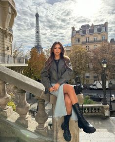 a woman sitting on top of a balcony next to the eiffel tower