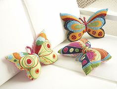 three colorful butterflies sitting on top of a white couch