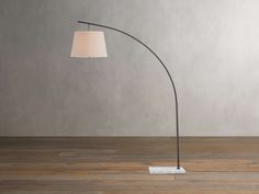 a floor lamp with a white shade on the base and a wooden floor in front of it