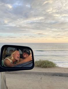 a man and woman taking a selfie in the side mirror of a car