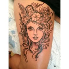 a woman's face with flowers and vines on her thigh, done in black ink