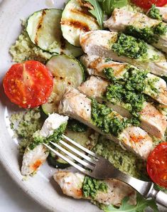 a white plate topped with chicken, cucumbers and tomatoes next to broccoli