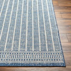 a blue and white area rug on the floor with wood floors in the background,