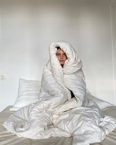 a woman wrapped in a blanket on top of a bed