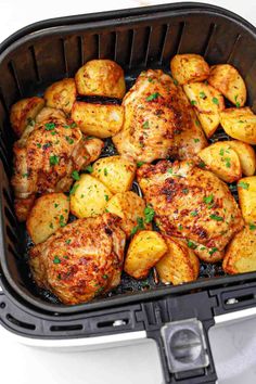 chicken and potatoes in an air fryer with parsley on the side, ready to be cooked