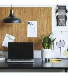 an open laptop computer sitting on top of a desk next to a plant and calendar