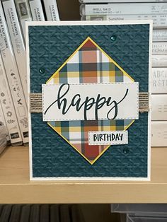 a happy birthday card on a shelf with books in the background and a pile of books behind it