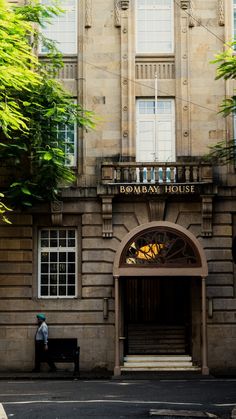 a man sitting on a bench in front of a building with an arched doorway and entrance