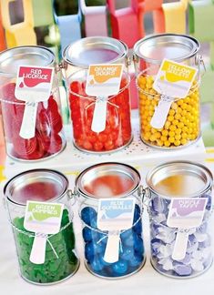 colorful candies are in buckets on a table with ribbons and tags attached to them