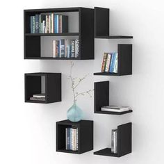 a wall mounted book shelf with books on it and a vase filled with flowers in the corner