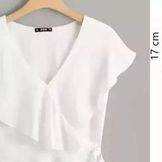 a white shirt with a tie on the front and bottom, next to a hanger