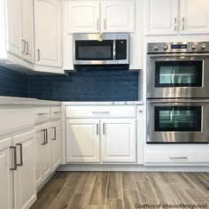 a kitchen with white cabinets and blue backsplash tiles on the wall, wood flooring