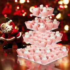 a christmas tree made out of cupcakes and santa claus figurine next to it