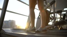 a woman standing on top of a treadmill with her legs crossed and feet propped up