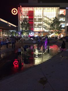 people are standing in the rain near a building at night with umbrellas and lights on