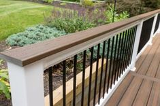 a close up of a wooden and metal railing on a deck with flowers in the background