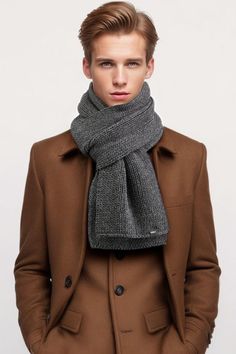 a young man wearing a brown coat and gray scarf over his head, standing in front of a white background