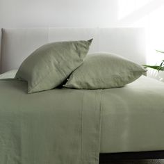 two pillows on top of a bed with green sheets