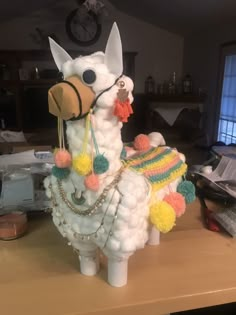 a llama made out of balloons sitting on top of a table next to a clock