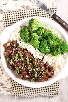 a white bowl filled with rice, meat and broccoli next to a knife