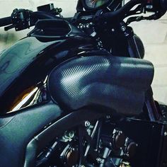 the motorcycle is parked in front of a white brick wall and has black leather seat covers on it