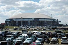 many cars are parked in front of a large building with a dome on the top