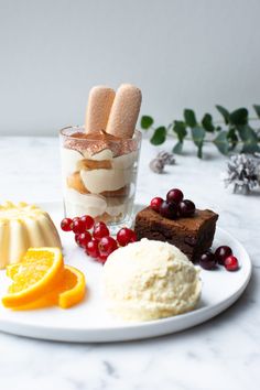 an assortment of desserts on a white plate with orange slices and cranberries