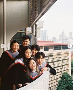 a group of young people standing on top of a balcony next to eachother