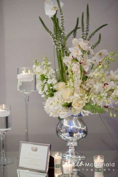 a vase filled with white flowers sitting on top of a table next to two candles