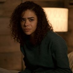 a woman with curly hair sitting on a bed