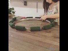 a woman is making a wreath out of cardboard and stringing it around the circle