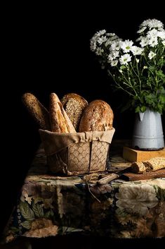 bread in a basket next to flowers on a table