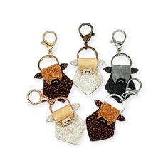 four keychains with different designs on them, one is brown and the other is white