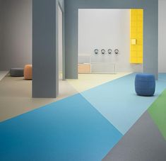 an empty room with multicolored flooring and blue, green, yellow, and grey furniture