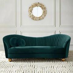 a green couch sitting on top of a rug in front of a wall mounted mirror