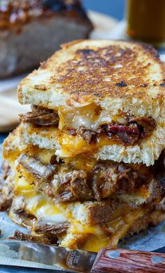 a grilled cheese sandwich stacked on top of each other next to a glass of beer