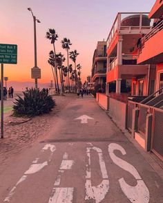 an empty street with palm trees on both sides and the word stop painted in white